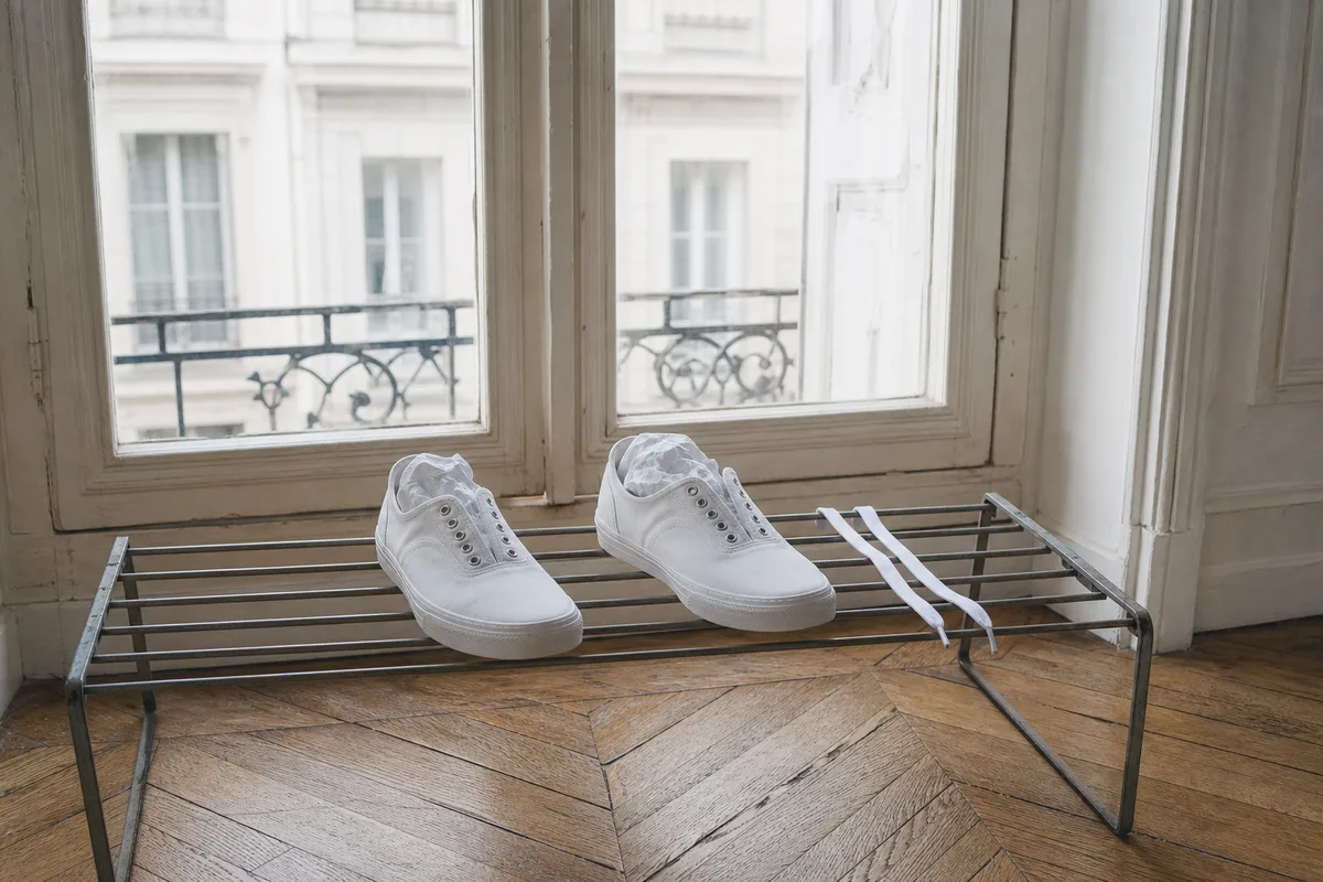 Baskets blanches en toile posées sur une grille de séchage devant une fenêtre d&rsquo;appartement français